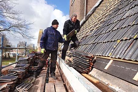 Kerkdak Scharsterbrug vernieuwdLast van een lekkend kerkdak hadden de leden van de Protestantse Gemeente Ouwsterhaule-Scharsterbrug niet direct, want vanwege de coronapandemie konden ze de zondagse diensten alleen via een live-stream volgen. Toch is het hele dak van de kerk uit 1904 van nieuwe panlatten voorzien en worden alle dakpannen opnieuw gelegd. Eerder eerdere reparatie hielp onvoldoende.Bouwbedrijf A. Fekken uit Scharsterbrug hoeft voor de zes weken durende klus alleen maar de weg over steken. Het bedrijf is pal tegenover de kerk uit 1914 gevestigd. Lieuwe Minnesma (l) en Siebren Kuperus leggen de pannen weer op hun plek. ,,Dizze pannen kinne noch in hiel skoftsje mei’’, aldus Minnesma, die uit Idskenhuizen afkomstig is. Een deel van het dakhout was verrot en is vernieuwd. Onder de panlatten is een vochtregulerende folie gelegd. Een deel van de zinken goten is ook vernieuwd.