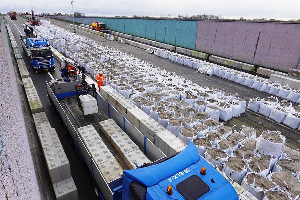 Een monsteroperatie is het transport van 2.300 Lego-betonblokken naar de gestremde Prinses Margriettunnel in de A7 tussen Joure en Sneek. Ze komen van Dam Beton in Akkrum, die ze als alternatief voor de 10.000 zandzakken aan Rijkswaterstaat aanbood. Beton is zwaarder dan zand en neemt minder ruimte in. Het Friese bedrijf had alle blokken vorig jaar al in de eigen, relatief nieuwe betoncentrale gemaakt en op eigen terrein klaar staan. Samen met staalplaten moeten de 2.400 kilo zware Lego-blokken de tunneldelen op hun plek houden. Het grondwater drukte de tunnelmoten los van hun ankers. Aannemer Van Hattum en Blankevoort maak in elke rijrichting een baan vrij voor verkeer en werkt daarna aan een oplossing voor het probleem, dat in de directe omgeving voor grote verkeersinfarcten zorgt. Over een half jaar kan Dam Beton weer aan de slag, want dan gaan de blokken weer retour naar de opslag in Akkrum of naar een nieuw werk.