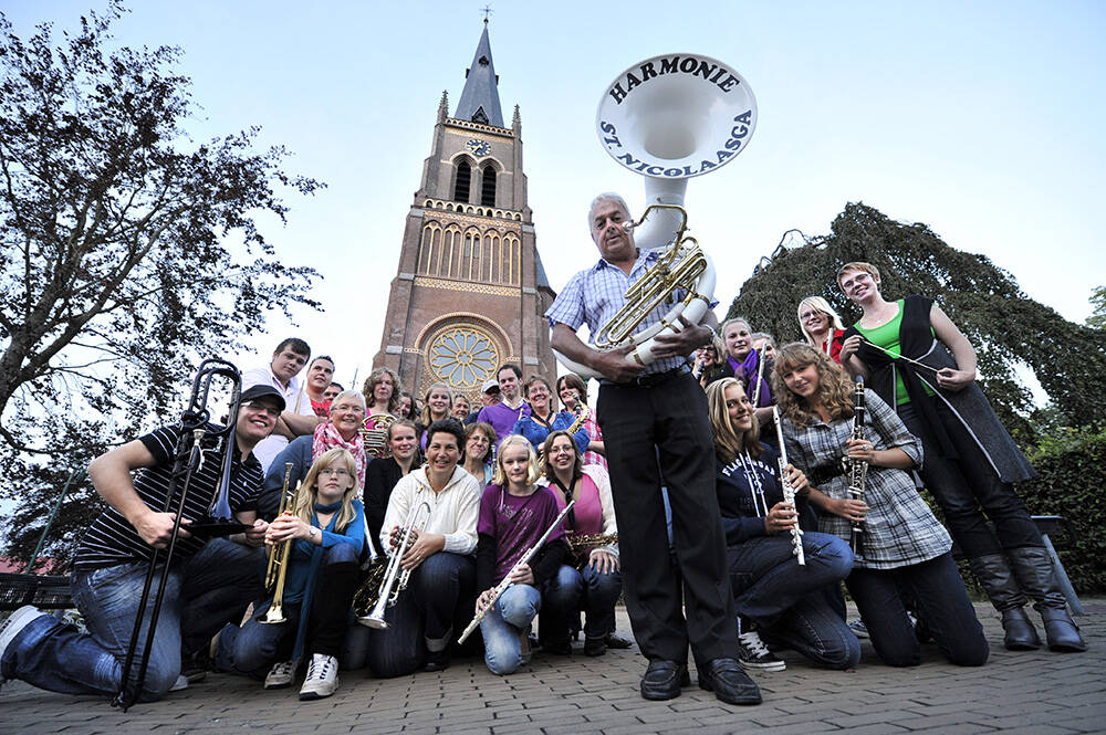 Frans Jellesma blaast tijdens de zestigste Allegoische Optocht in Sint Nicolaasga voor de zestigste keer zijn partijtje mee. Op de foto staat hij met zijn sousafoon en de leden van muziekvereniging De Harmonie voor de rooms-katholieke kerk van het dorp.